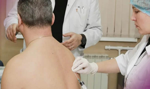 Врач делает укол пациенту в спину